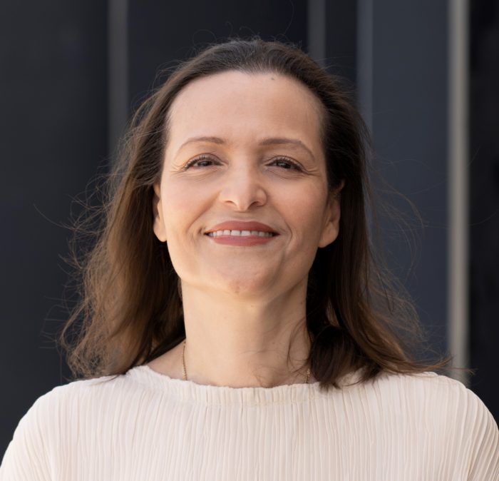 Femme souriante aux cheveux bruns portant un chandail blanc