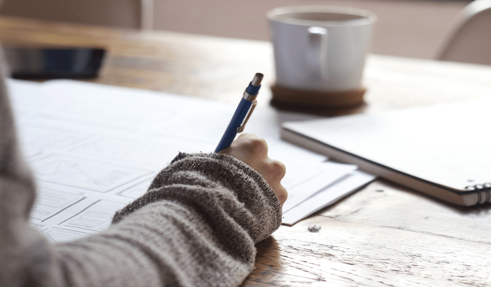 Plan rapproché montrant une main tenant un stylo et écrivant sur du papier.