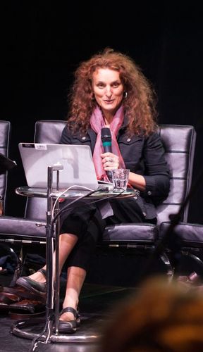Portrait d'une femme assise sur un siège, face à un ordinateur portable.